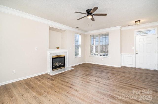 unfurnished living room featuring light wood-type flooring, a fireplace, and crown molding