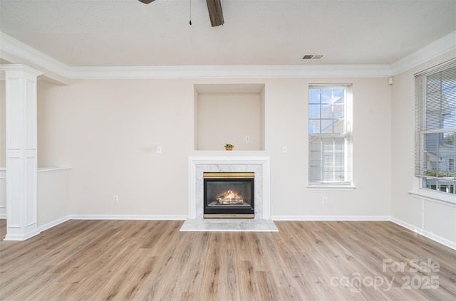 unfurnished living room featuring crown molding, decorative columns, visible vents, light wood-style flooring, and a premium fireplace