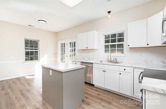 kitchen with a sink, stainless steel appliances, a kitchen island, and white cabinets