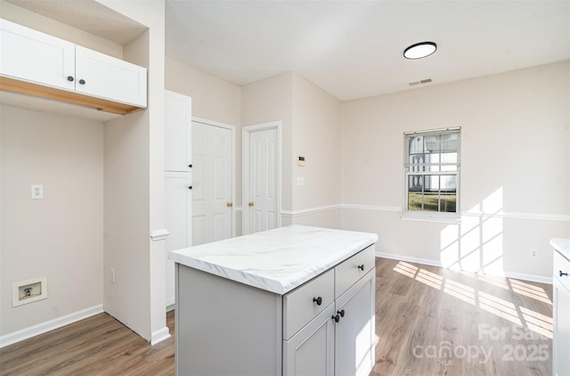 kitchen with light countertops, a kitchen island, and light wood finished floors