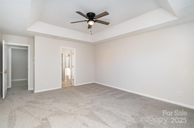 unfurnished bedroom featuring carpet, a tray ceiling, baseboards, and ensuite bathroom