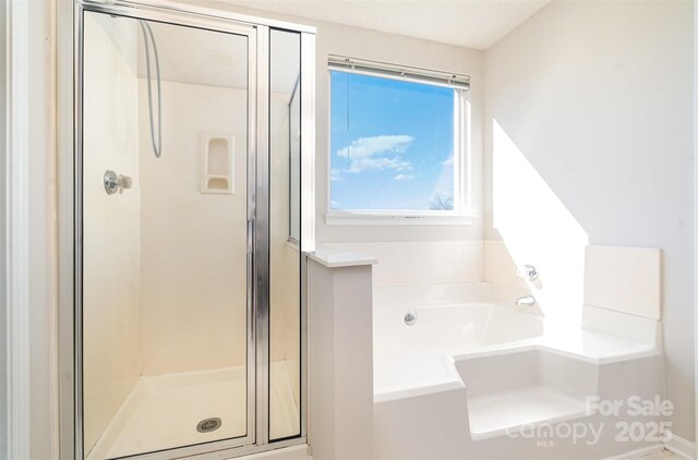 bathroom featuring a garden tub and a shower stall