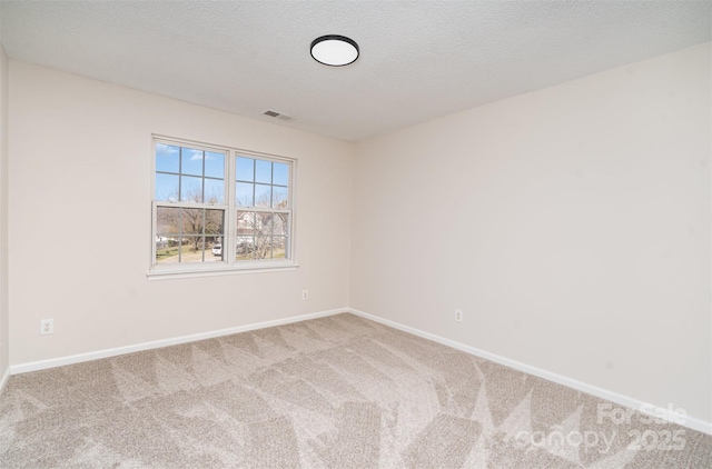 empty room featuring light carpet, a textured ceiling, visible vents, and baseboards