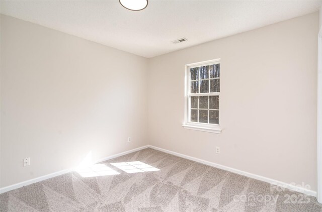 empty room featuring carpet flooring, visible vents, and baseboards