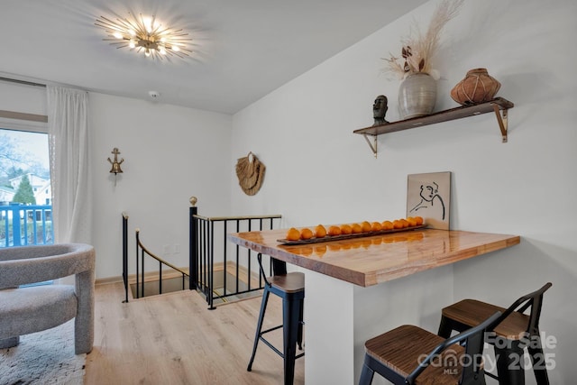 interior space featuring a kitchen bar, butcher block counters, kitchen peninsula, and light wood-type flooring