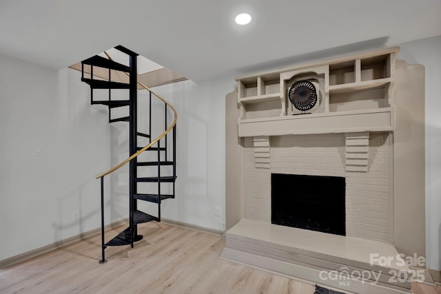 stairs featuring wood-type flooring and a brick fireplace