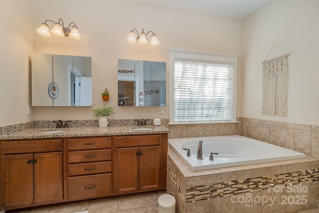 bathroom featuring tile patterned floors, vanity, and tiled bath