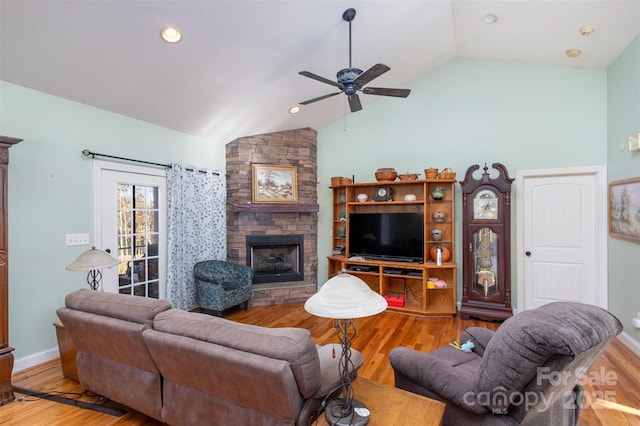 living room with a stone fireplace, ceiling fan, lofted ceiling, and hardwood / wood-style flooring