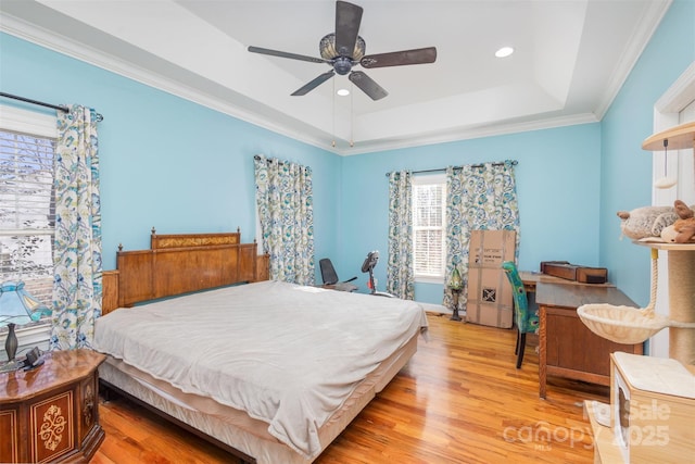 bedroom with a raised ceiling, ceiling fan, crown molding, and light hardwood / wood-style floors