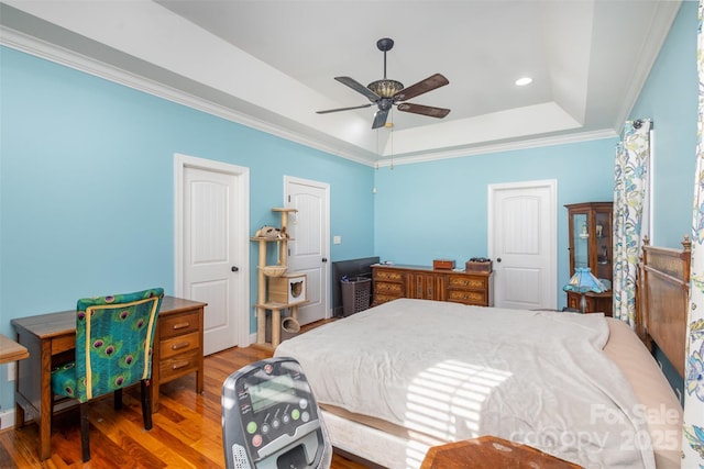 bedroom featuring a tray ceiling, ceiling fan, crown molding, and hardwood / wood-style flooring