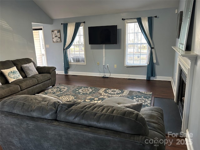 living room featuring plenty of natural light, dark hardwood / wood-style flooring, and vaulted ceiling