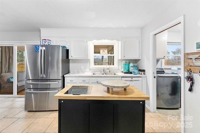 kitchen with stainless steel refrigerator, white cabinetry, a kitchen island, and light tile patterned floors