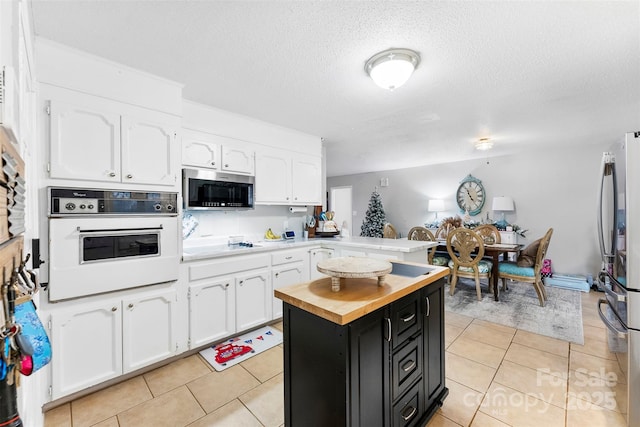 kitchen with white cabinets, a center island, light tile patterned flooring, and appliances with stainless steel finishes