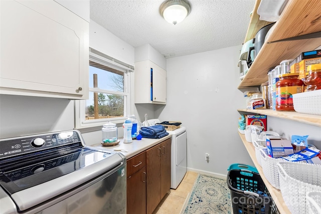 washroom featuring cabinets, light tile patterned floors, a textured ceiling, and washing machine and dryer