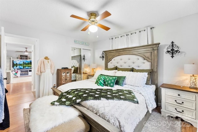 bedroom with ceiling fan, light wood-type flooring, and a textured ceiling