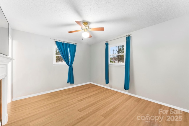 empty room with ceiling fan, light hardwood / wood-style floors, and a textured ceiling