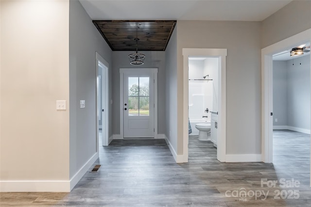 foyer with ceiling fan with notable chandelier, hardwood / wood-style flooring, and wooden ceiling