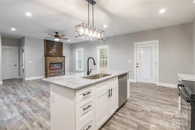 kitchen featuring white cabinetry, sink, ceiling fan, a fireplace, and appliances with stainless steel finishes