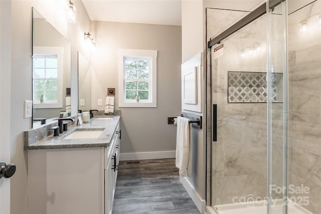 bathroom featuring hardwood / wood-style flooring, vanity, a healthy amount of sunlight, and walk in shower