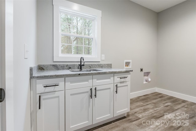 washroom featuring hookup for an electric dryer, hookup for a washing machine, cabinets, sink, and light hardwood / wood-style floors