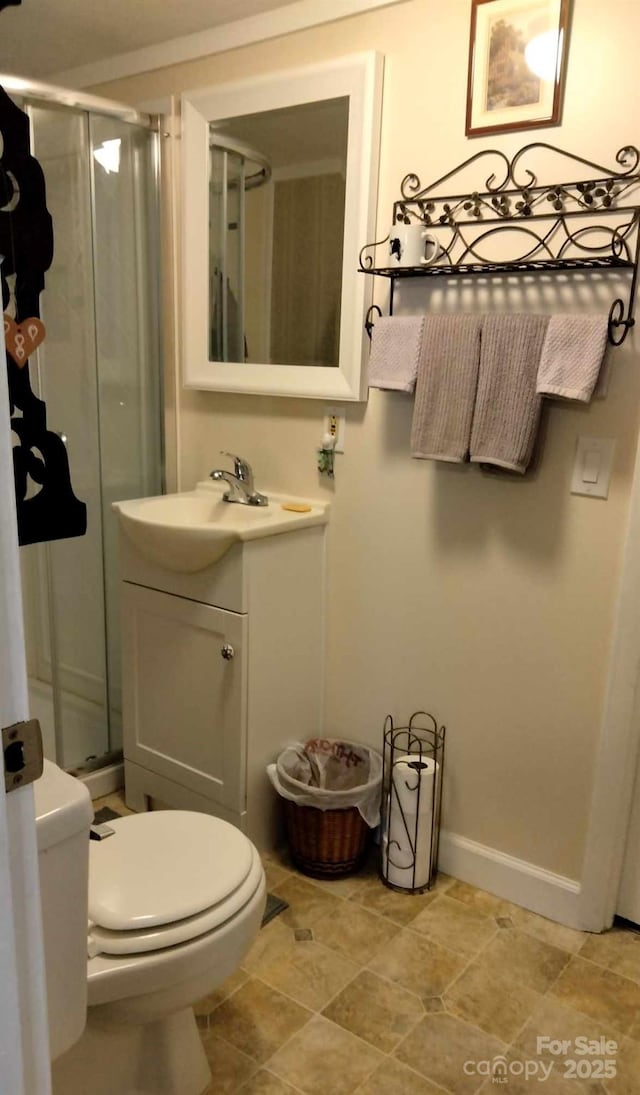 full bathroom featuring toilet, a shower stall, vanity, and baseboards