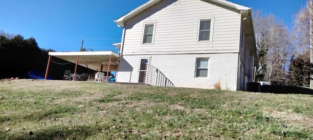 back of property featuring a lawn and brick siding