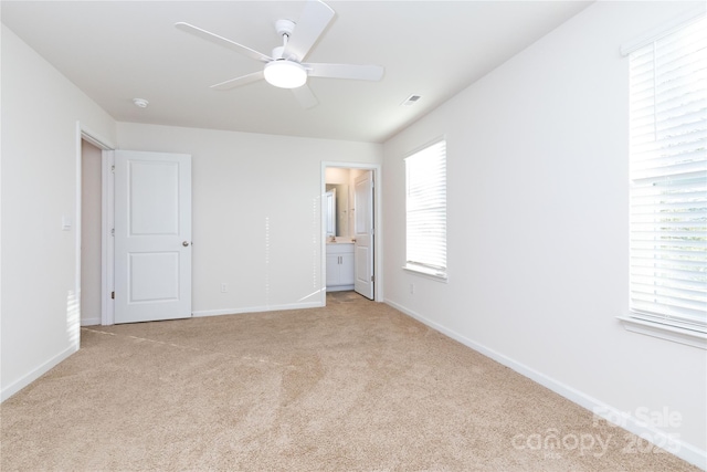 unfurnished bedroom with ensuite bath, ceiling fan, and light carpet