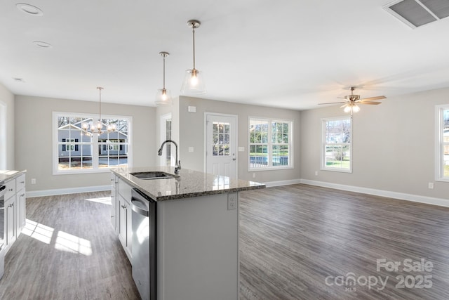 kitchen with sink, a center island with sink, stainless steel dishwasher, stone counters, and pendant lighting