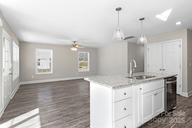 kitchen featuring sink, a kitchen island with sink, hanging light fixtures, light stone counters, and white cabinets