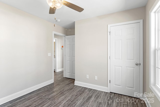 unfurnished bedroom featuring dark wood-type flooring, ceiling fan, a closet, and multiple windows