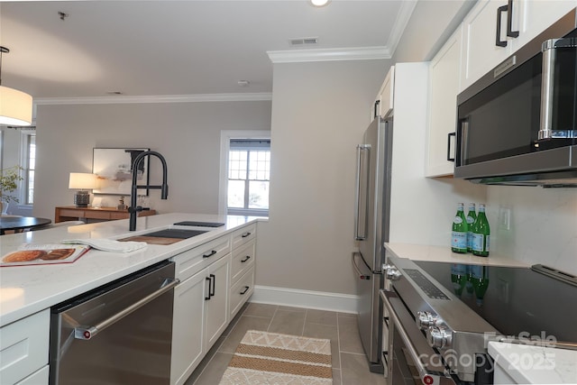 kitchen featuring high quality appliances, dark tile patterned flooring, sink, light stone counters, and white cabinetry