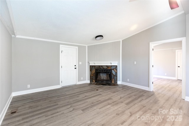 unfurnished living room featuring a stone fireplace, ornamental molding, and light hardwood / wood-style flooring