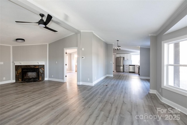 unfurnished living room featuring light hardwood / wood-style floors, a stone fireplace, a wealth of natural light, and lofted ceiling