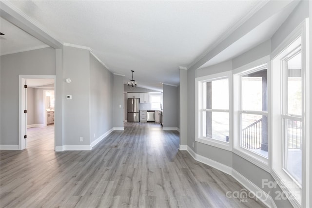 unfurnished living room featuring a chandelier, light hardwood / wood-style floors, crown molding, and vaulted ceiling