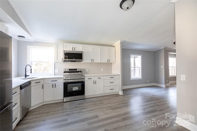 kitchen with crown molding, sink, white cabinets, and stainless steel appliances