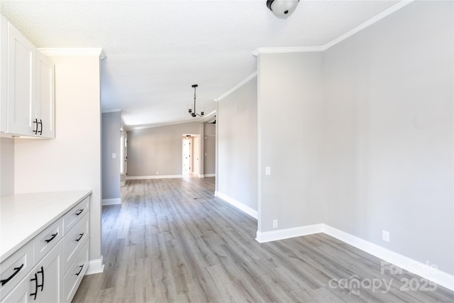 interior space with lofted ceiling, light hardwood / wood-style floors, ornamental molding, and a textured ceiling