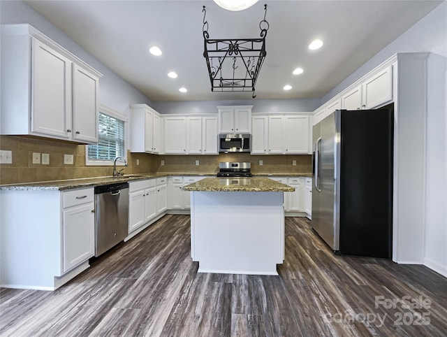 kitchen with a center island, dark stone counters, dark hardwood / wood-style flooring, white cabinetry, and stainless steel appliances