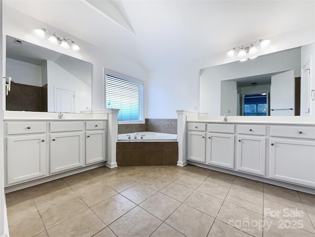 bathroom featuring tile patterned floors, vanity, and a relaxing tiled tub