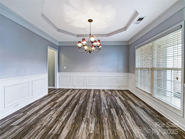 unfurnished dining area with a chandelier, dark hardwood / wood-style flooring, a tray ceiling, and a healthy amount of sunlight