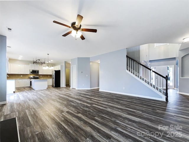 unfurnished living room with ceiling fan with notable chandelier and dark hardwood / wood-style floors