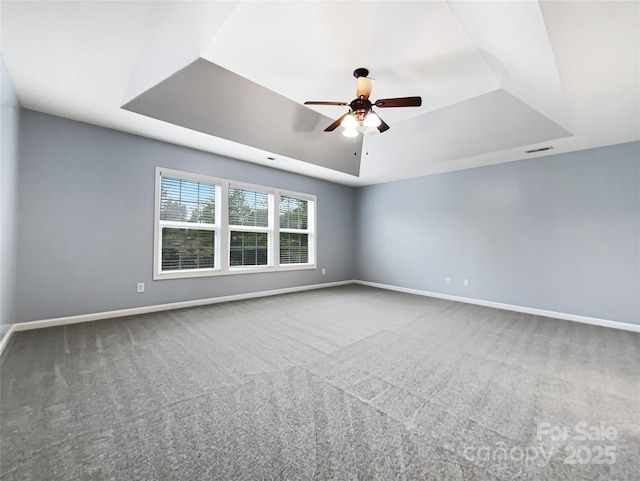 spare room with ceiling fan, a raised ceiling, and carpet floors