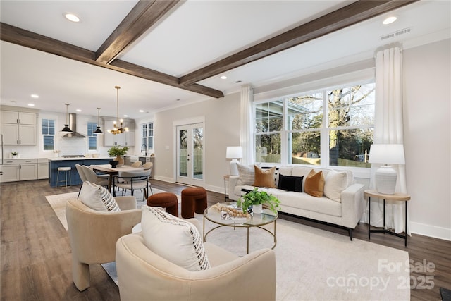 living room with beam ceiling, hardwood / wood-style floors, and a notable chandelier