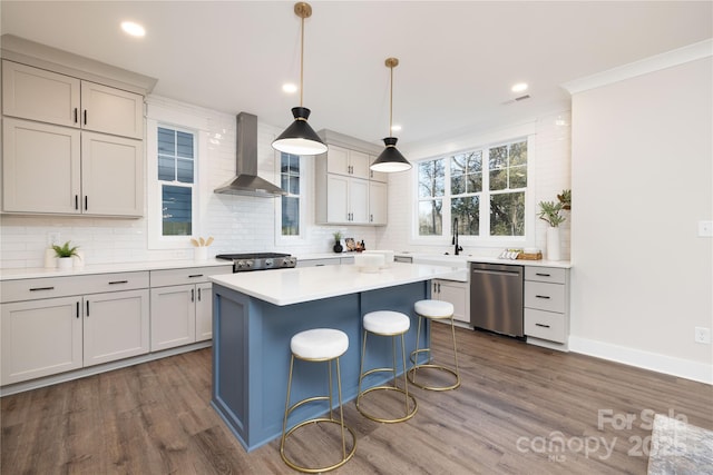 kitchen with appliances with stainless steel finishes, dark hardwood / wood-style flooring, wall chimney exhaust hood, pendant lighting, and a center island