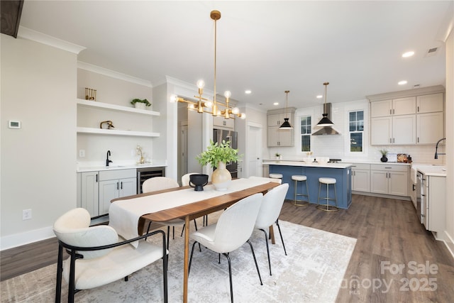 dining area with hardwood / wood-style flooring, beverage cooler, a notable chandelier, and sink