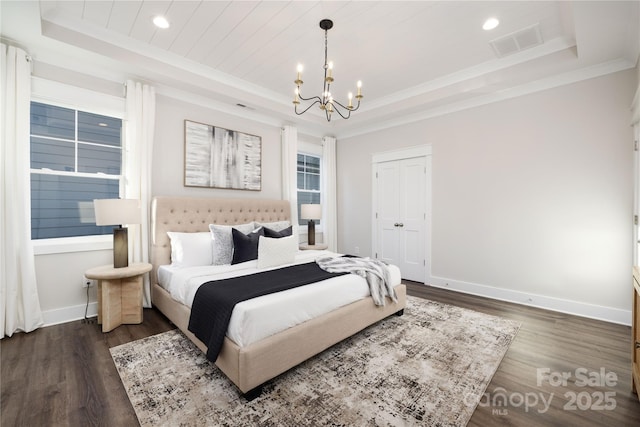 bedroom featuring a tray ceiling, dark hardwood / wood-style floors, and a notable chandelier