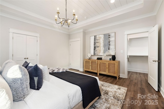 bedroom with a chandelier, a tray ceiling, and dark wood-type flooring