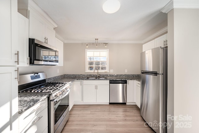 kitchen with sink, dark stone counters, ornamental molding, stainless steel appliances, and white cabinets