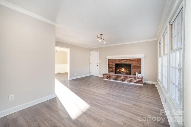 unfurnished living room featuring ornamental molding, a brick fireplace, and light hardwood / wood-style flooring