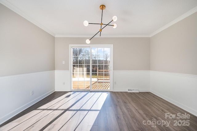 unfurnished dining area featuring hardwood / wood-style flooring, crown molding, and a notable chandelier