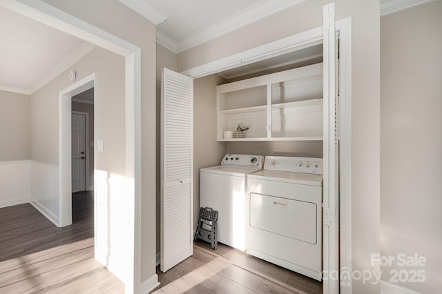 washroom with ornamental molding, separate washer and dryer, and light wood-type flooring